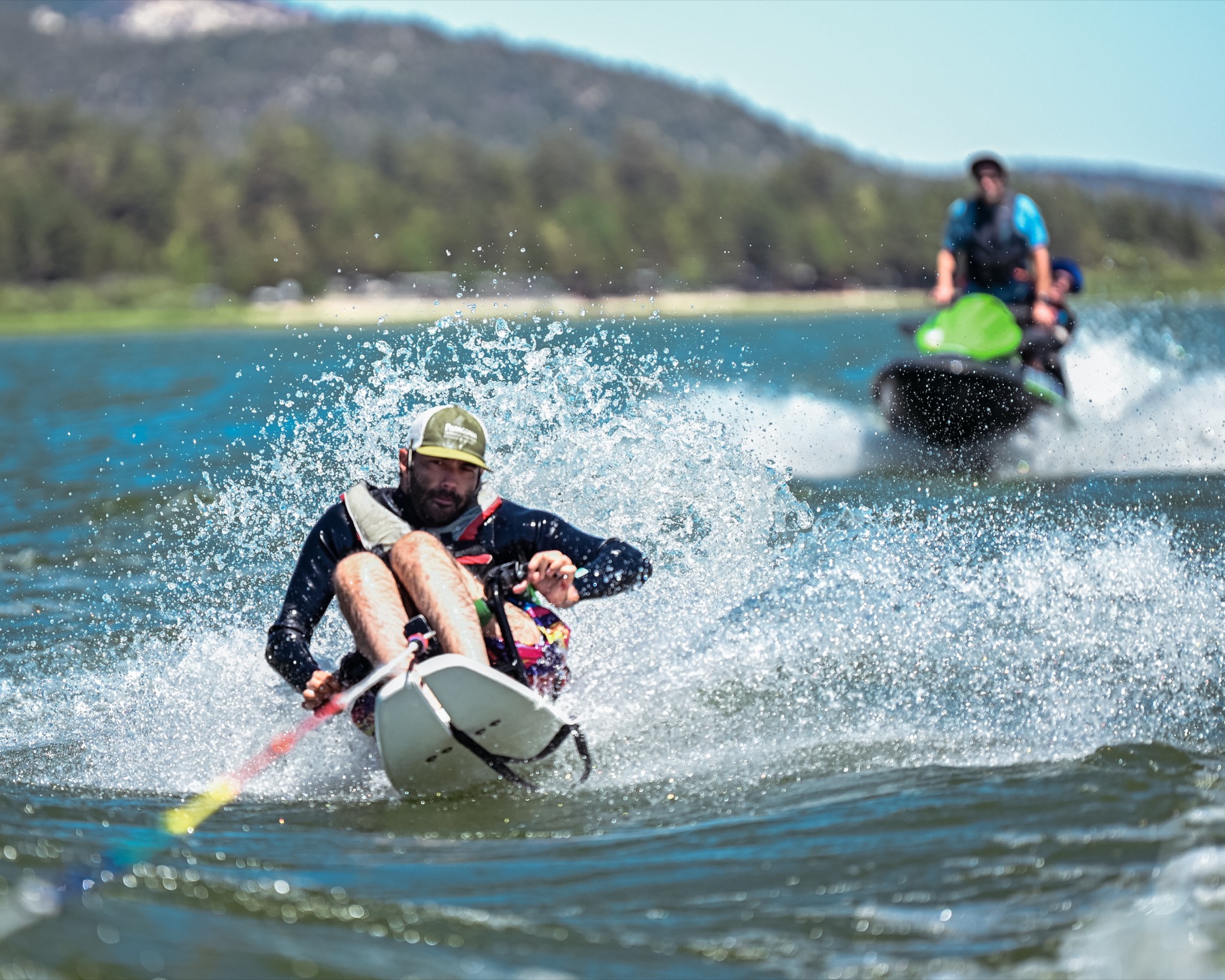 A participant on an adaptive water ski grips the tow rope while a volunteer follows on a personal watercraft across Big Bear Lake.